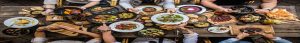 spread of food and drink on a table with people eating